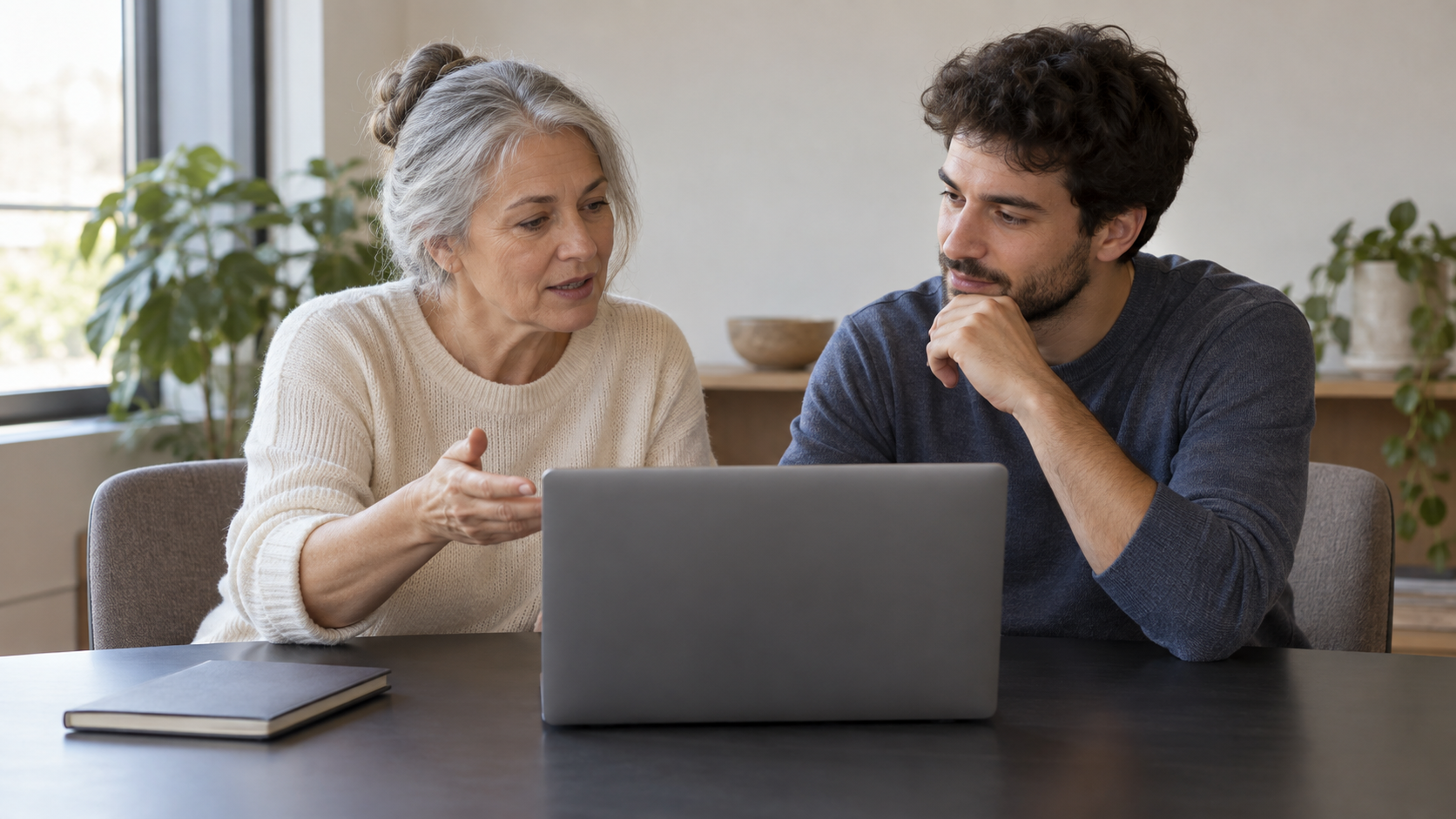 Two software maintainers discussing a laptop during a knowledge handover